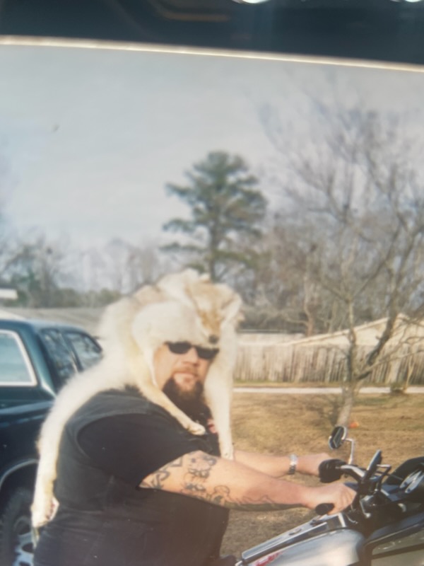 Marcus seated on a motorcycle wearing a fur hat